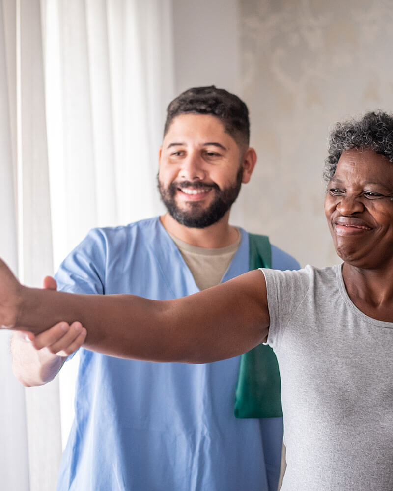 Young male nurse assisting elderly woman with physical therapy