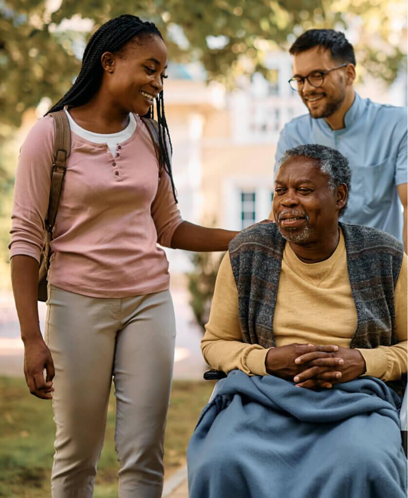 Elderly male in wheelchair with nurse and granddaughter with him